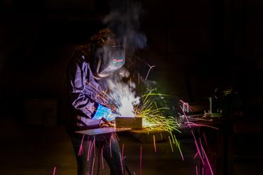 woman welding with colorful sparks flying. Senior photos.