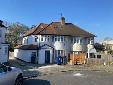 A semi-detached house under a clear blue sky in a suburban area.