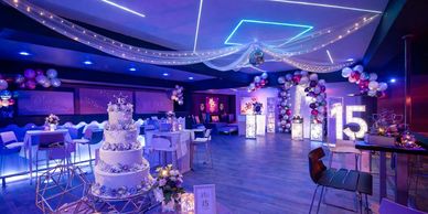 Decorated venue for a 15th birthday celebration with cake and lights.
