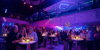 People celebrating a 50th birthday party in a lively, colorful venue.