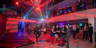 People socializing in a vibrant nightclub with colorful laser lights.