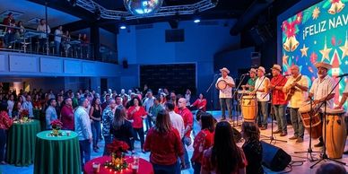 A festive crowd enjoys live music at a holiday event with vibrant decorations.