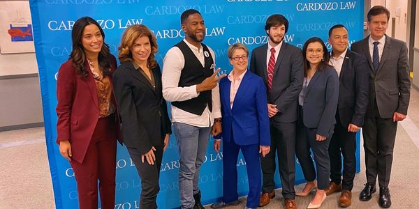 Group photo at Cardozo Law with smiling individuals in formal and casual attire.