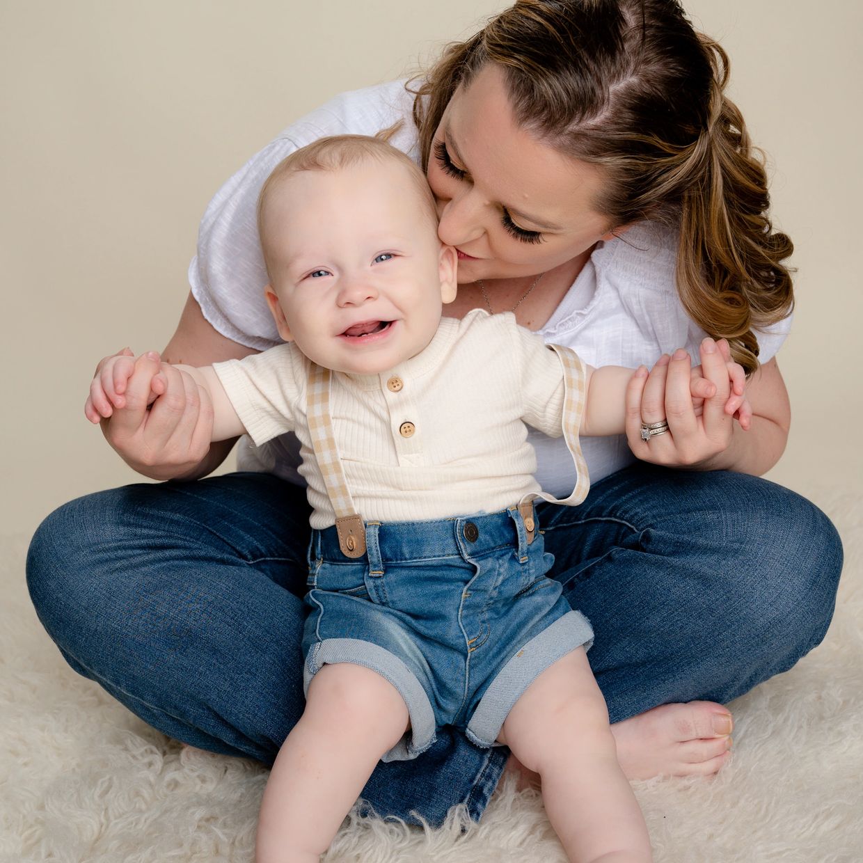 Mom kisses baby on cheek during a milestone session in an Austin family photography studio. 
