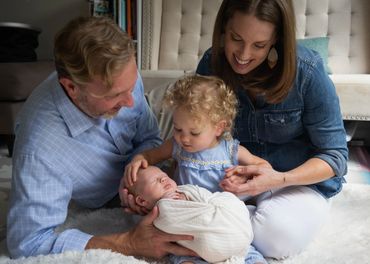 Family newborn in-home photoshoot where sibling holds baby sister