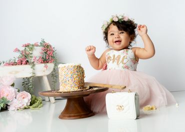 Cake smash for first birthday girl wearing pink dress for birthday photo session in Austin, Texas