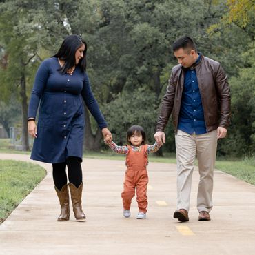 Couple walk with baby during their outdoor family photoshoot in an Austin, Texas park. 