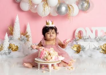 Baby eats cake during first birthday cake smash photo shoot in Austin, Texas photo studio. 