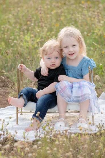 Siblings pose on prop bed during an outdoor family photoshoot in an Austin, Texas park. 