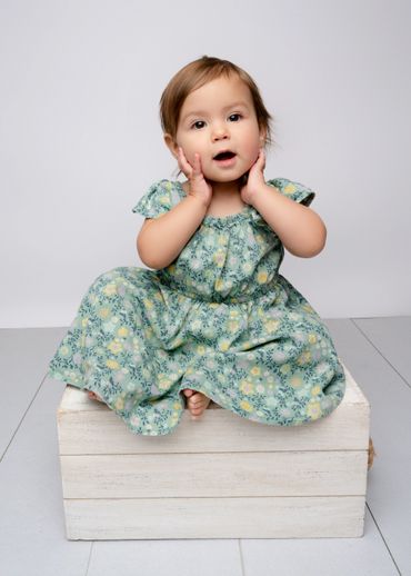 Baby poses on a box for her milestone photo session in an Austin, Texas photography studio. 