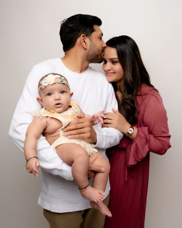 Dad kisses mom while they hold their baby during a studio family photo shoot in Austin, Texas. 