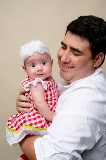 Dad holds smiling baby for a studio family photoshoot. 