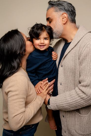 Mom and Dad kiss the baby during their first birthday cake smash photo session in Austin