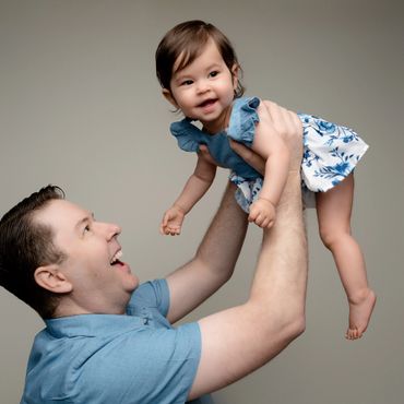 Dad holds baby in the air during a first birthday photoshoot in Austin Texas photo studio