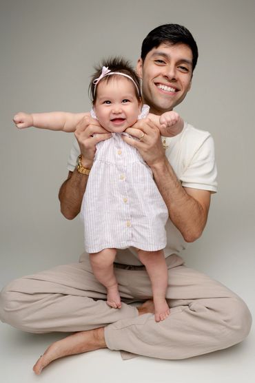 Dad holds smiling baby during a milestone photography session in Austin, Texas photo studio. 