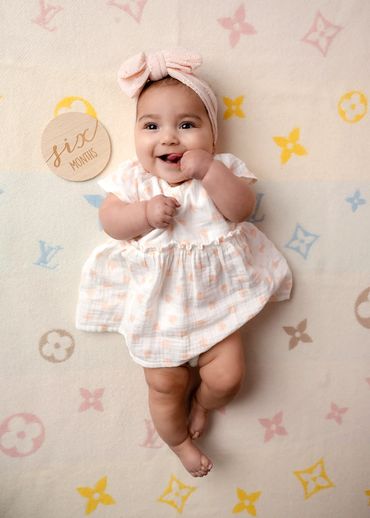 Girl poses on her back during a milestone photoshoot with an Austin, Texas baby photographer.