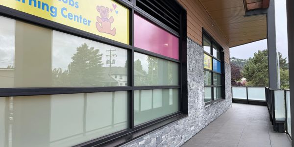 Exterior corridor of a kids learning center with stone walls and frosted windows.