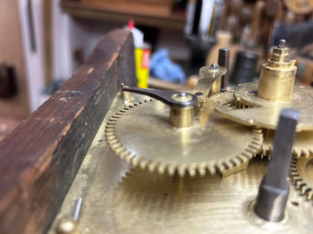 wheels from a lantern clock are displayed on a working bench