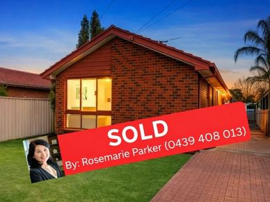 Brick house with sold sign by Rosemarie Parker at sunset.