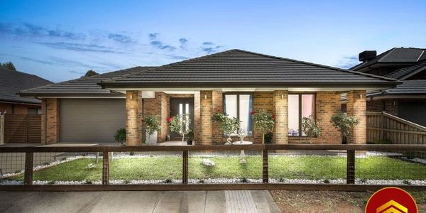 Modern brick house with a neat front yard and wooden fence at dusk.