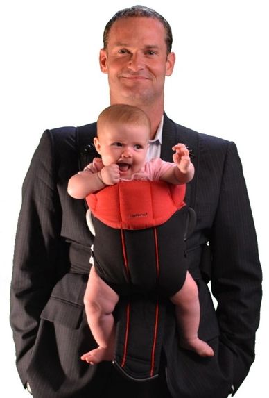 Dr. Daniel Singley wearing a business suit wearing a baby carrier. 