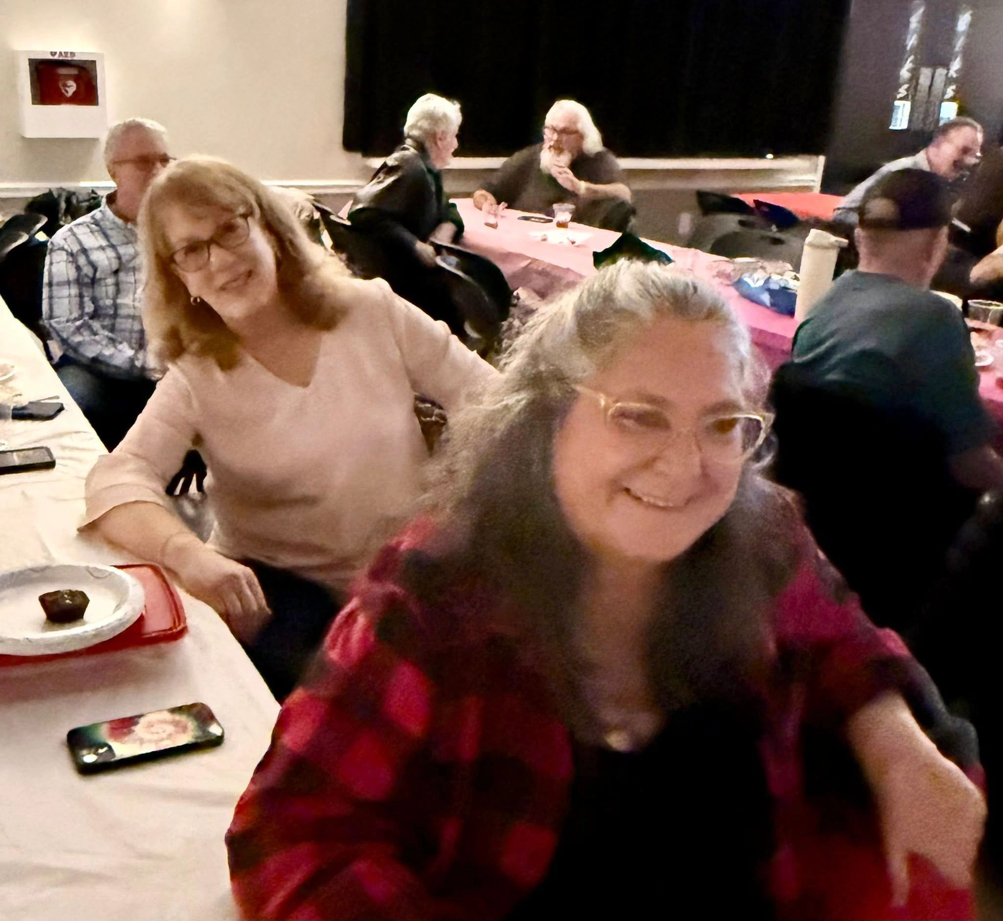 Group of people enjoying a casual gathering around tables with food and drinks.