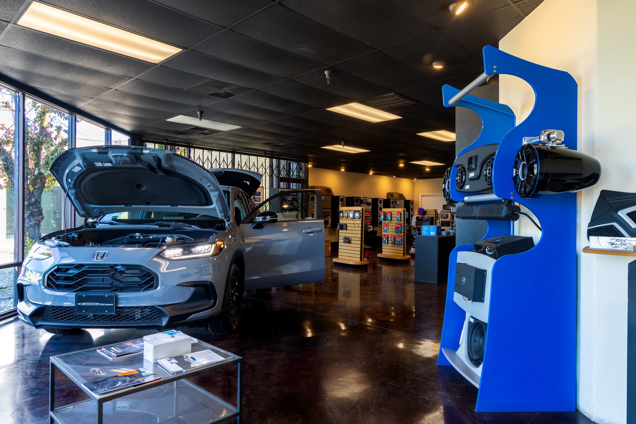 Car with open hood inside an audio equipment store.