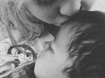 A child kissing a baby's head.