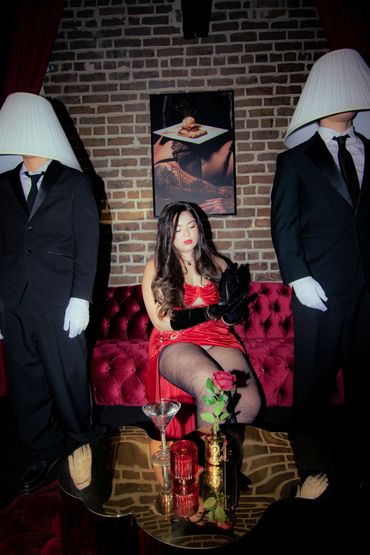 Woman in red dress with two men wearing lampshades on their heads.
