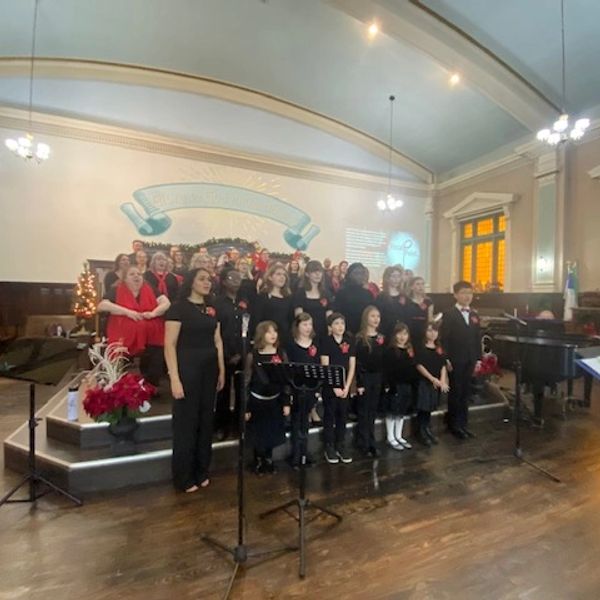 Choir group performing on stage in a decorated hall.