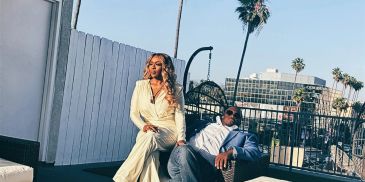 Stylish couple relaxing on outdoor patio under palm trees.