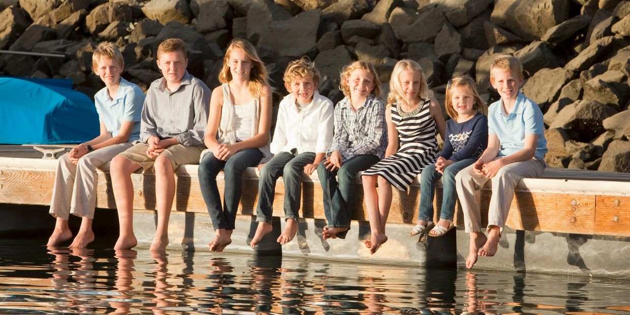 Family session with cousins, all sitting on a dock at the San Diego Yacht Club on a sunny day. 