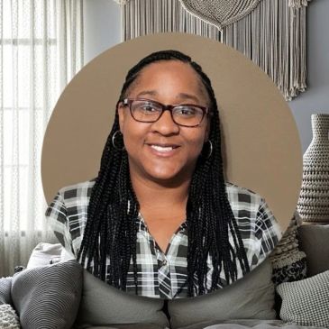 Portrait of a smiling woman with glasses and braided hair.