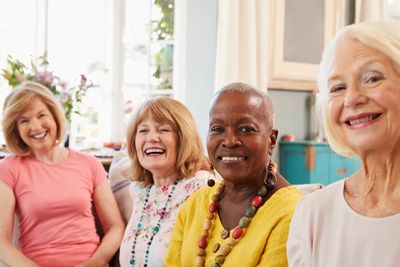 Four women gathered for a cryotherapy party, smiling warmly in a bright room.