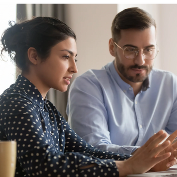 Two colleagues discussing work while looking at a laptop screen.