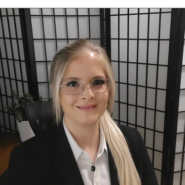 Professional woman with glasses smiling in a modern office setting.