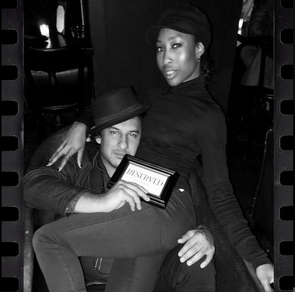 Couple posing with a reserved sign in a cozy setting.