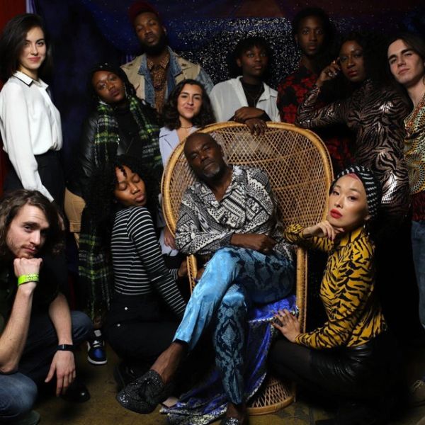 Group of diverse people posing with a man in a wicker chair.