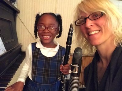 Teacher and student smiling with clarinet and piano.