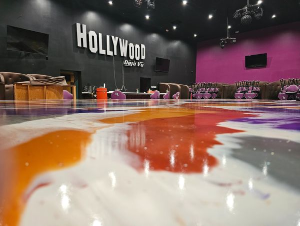 Empty Hollywood Deja Vu club room with colorful floor and stacked chairs.
