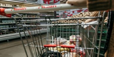 Grocery cart filled with food items in a supermarket aisle.