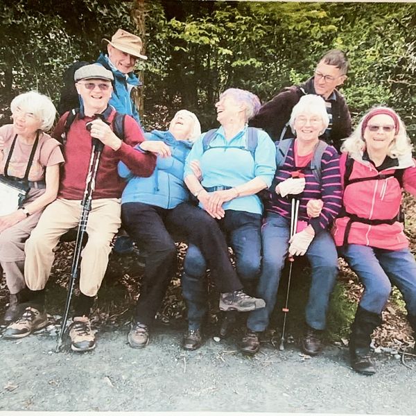 A joyful group of elderly friends resting outdoors during a hike.
