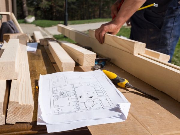 Carpenter making wooden structure outside, general carpentry