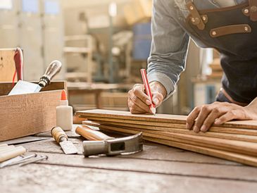 Carpenter working with equipment on wooden table in carpentry shop