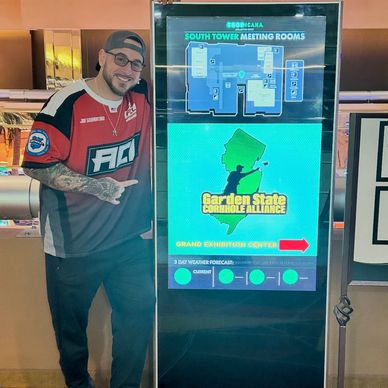 Man poses next to a sign for Garden State Cornhole Alliance at Tropicana Atlantic City.