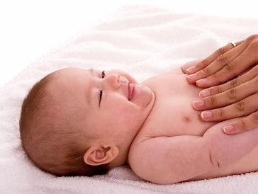 Smiling baby lying on a towel with hands gently on chest.
