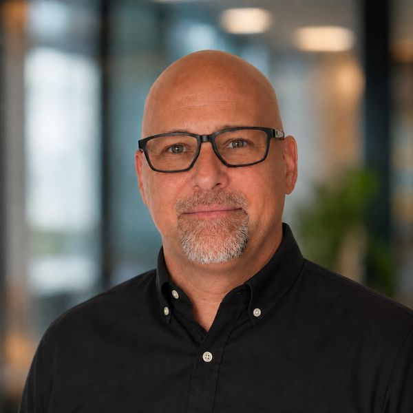 Bald man with glasses and goatee smiling at the camera.