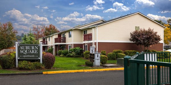Auburn Square apartment complex with manicured landscaping and cloudy sky.