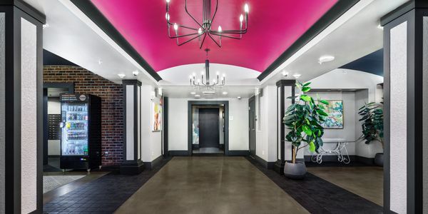 Modern lobby with bright pink ceiling and elegant lighting fixtures.