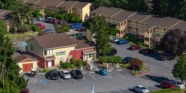 Apartment complex with parking lot and leasing office under bright daylight.